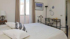 Et soveværelse med en seng, et skrivebord, en stol, en lampe og et billede på væggen.