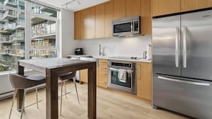 Una cocina moderna con electrodomésticos de acero inoxidable, armarios de madera y un comedor con mesa y sillas.