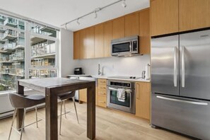 Eine moderne Küche mit Edelstahlgeräten, Holzschränken und einem Essbereich mit Tisch und Stühlen.
