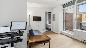Una habitación con escritorio, computadora, silla y un amplio ventanal.