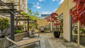 Un cortile con un’area salotto, una scala e un edificio con ampie finestre.