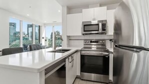 Una cucina moderna con elettrodomestici in acciaio inossidabile, una grande isola e vista sulla città.
