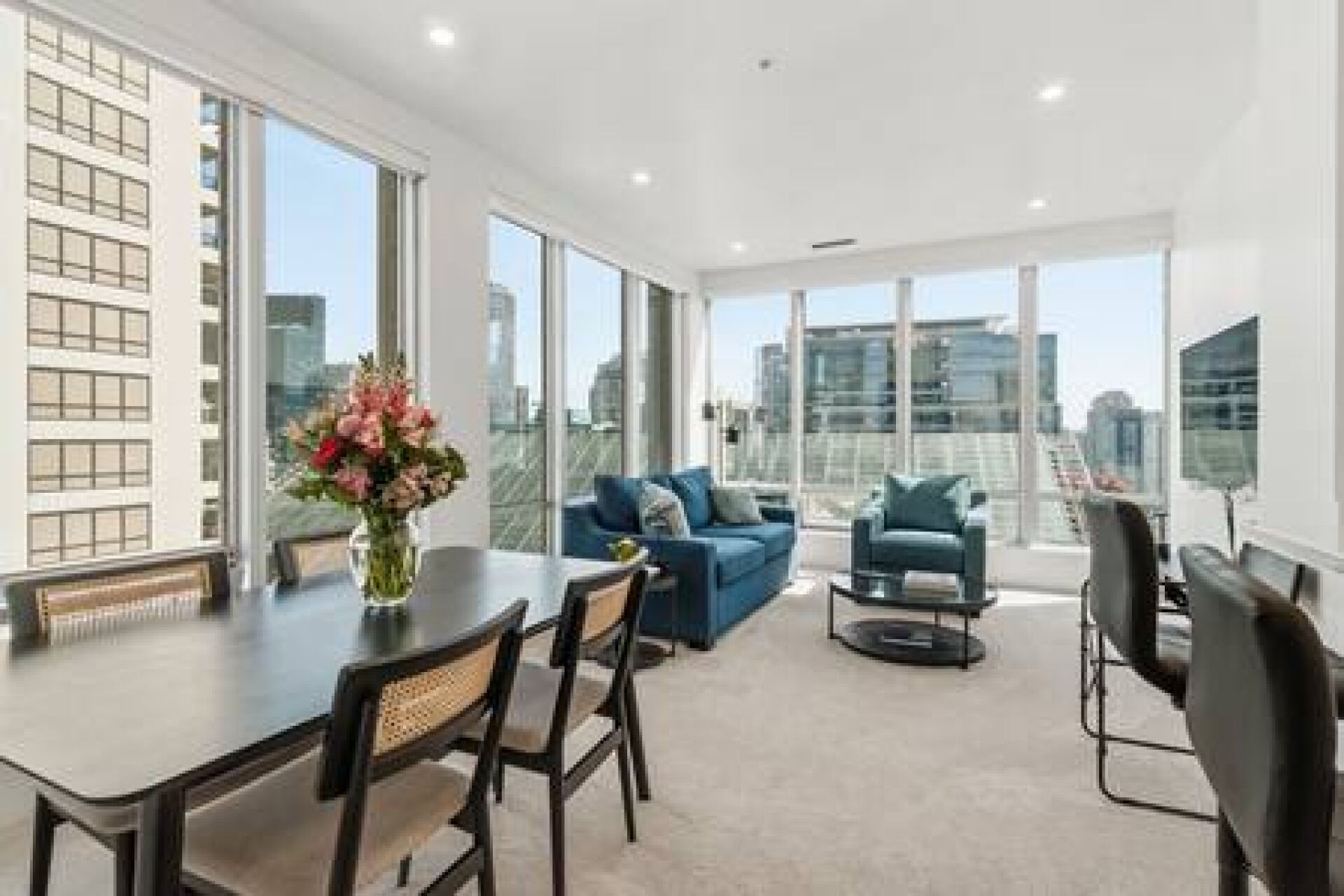 A modern living room with a dining table, chairs, a sofa, and a TV.