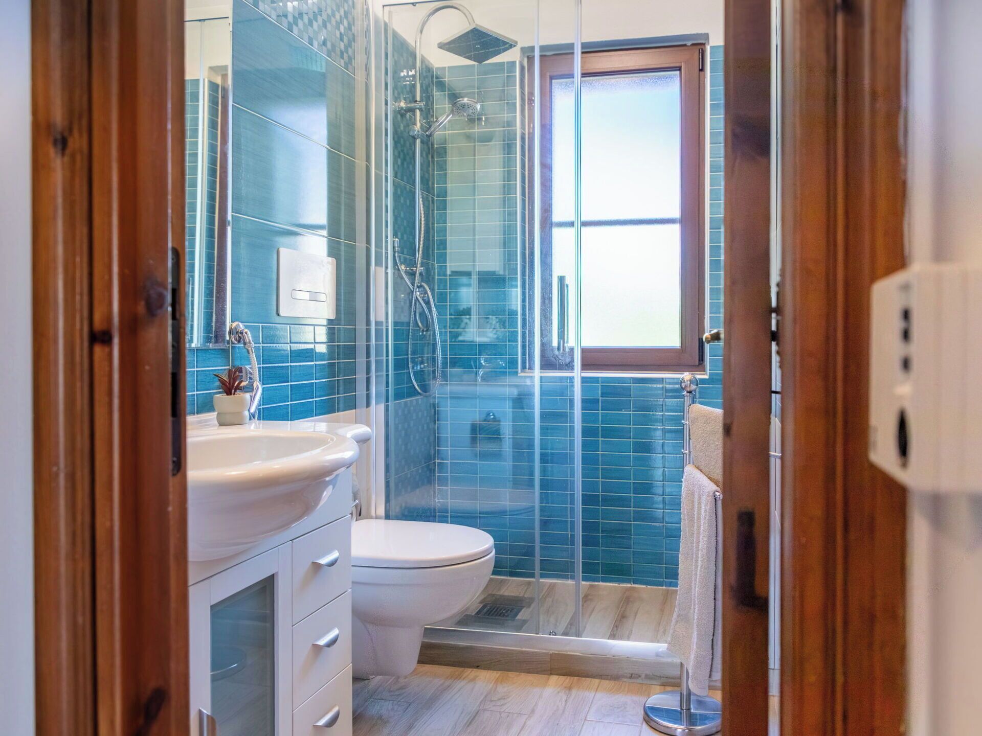 Ein Badezimmer mit Duschkabine aus Glas, einer weißen Toilette und einem Waschbecken mit Schrank.