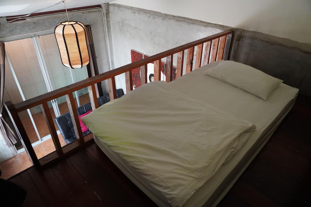 A bedroom with a wooden bed, a hanging light fixture, and a view of the outside.