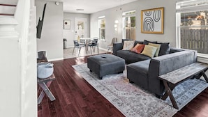 A modern living room with a gray sofa, ottoman, and a ceiling fan. - Exclusive Bourbon retreat close to Nulu Downtown! (Louisville)