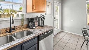A kitchen with granite countertops, a dishwasher, a coffee maker, and wooden cabinets. - Exclusive Bourbon retreat close to Nulu Downtown! (Louisville)