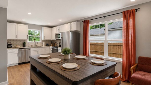 Una cocina moderna con armarios blancos, electrodomésticos de acero inoxidable y una isla central con asientos.