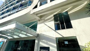 Un edificio moderno con fachada de vidrio, un cartel que dice 'bahamas' y un cielo azul despejado.