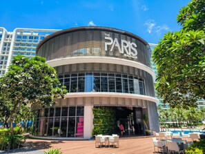 Un edificio moderno con una facciata curva, ampie finestre e un cartello con la scritta 'The Paris Beach Club'.
