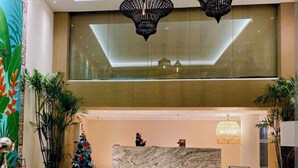 Un vestíbulo con una mesa de recepción, un árbol de Navidad y plantas en macetas.
