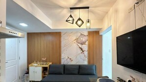 Un dormitorio moderno con una cama, un televisor, un escritorio y un adorno en la pared.