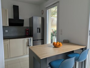 Una cocina moderna con un refrigerador integrado, una cafetera y un tazón de naranjas en la encimera.