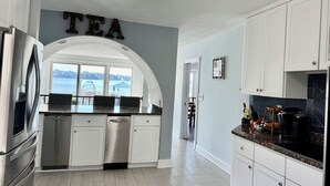 Una cucina moderna con mobili bianchi, un frigorifero in acciaio inossidabile, una lavastoviglie e un piano di lavoro con vista sul lago.