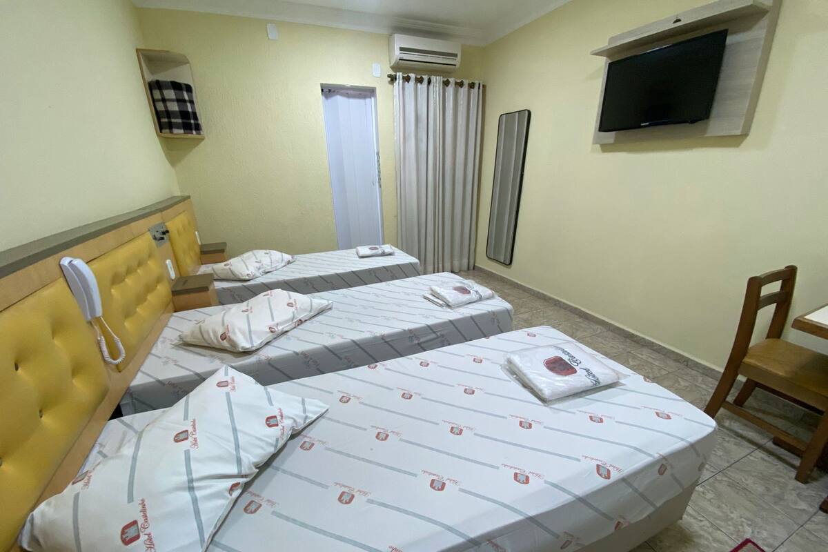 Ein Hotelzimmer mit zwei Betten, einem Telefon, einem Fernseher und einem Sessel.