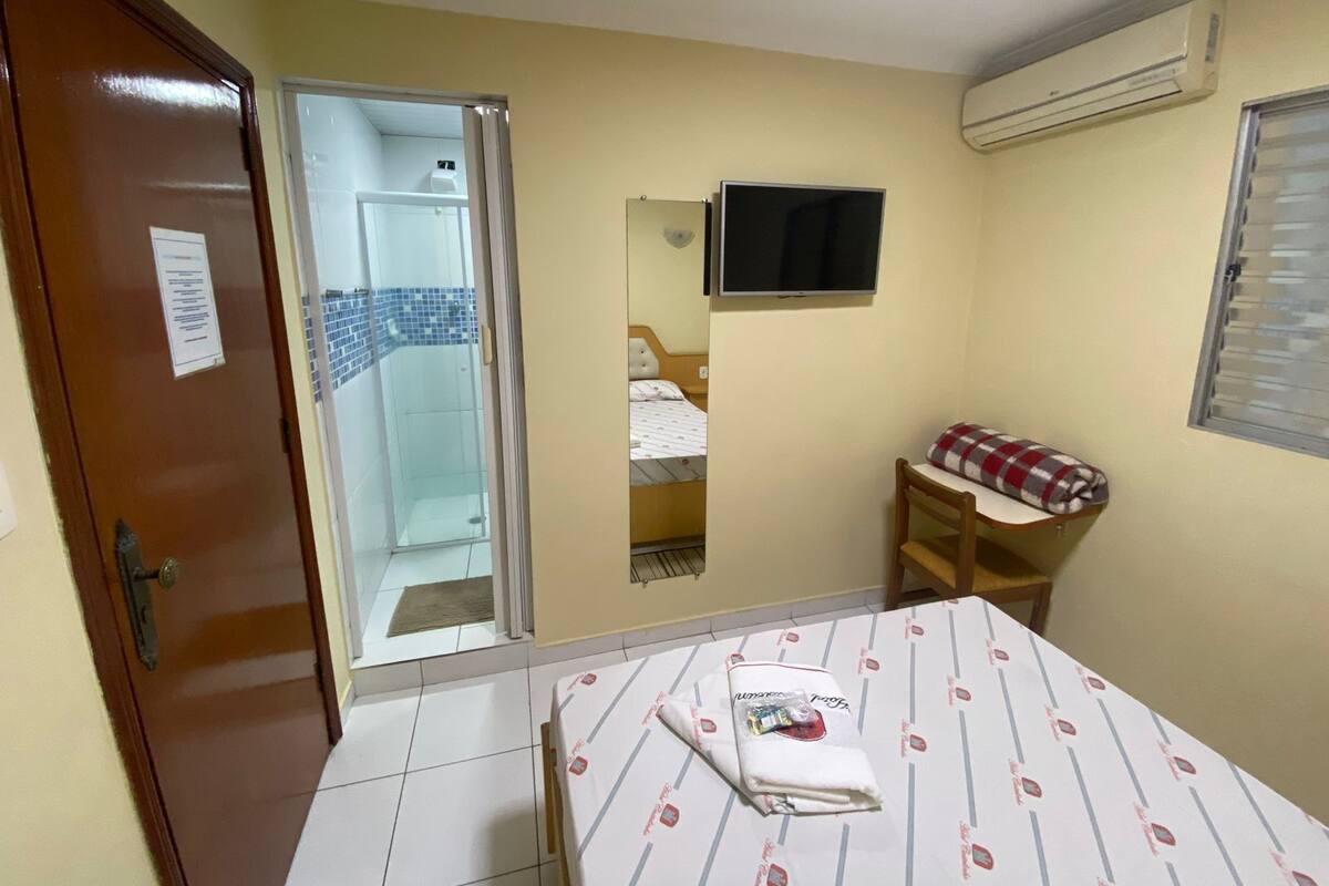 Ein Schlafzimmer mit Bett, Fernseher, Stuhl und Kleiderschrank.