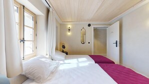 Un dormitorio con dos camas, una ventana, un espejo y una puerta.