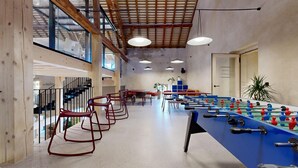 Amplio espacio interior con mesa de fútbol, sillas rojas y una escalera.