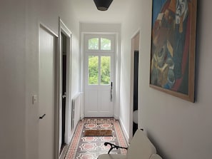 Ein Flur mit gemustertem Boden, einer weißen Tür und einem Gemälde an der Wand.