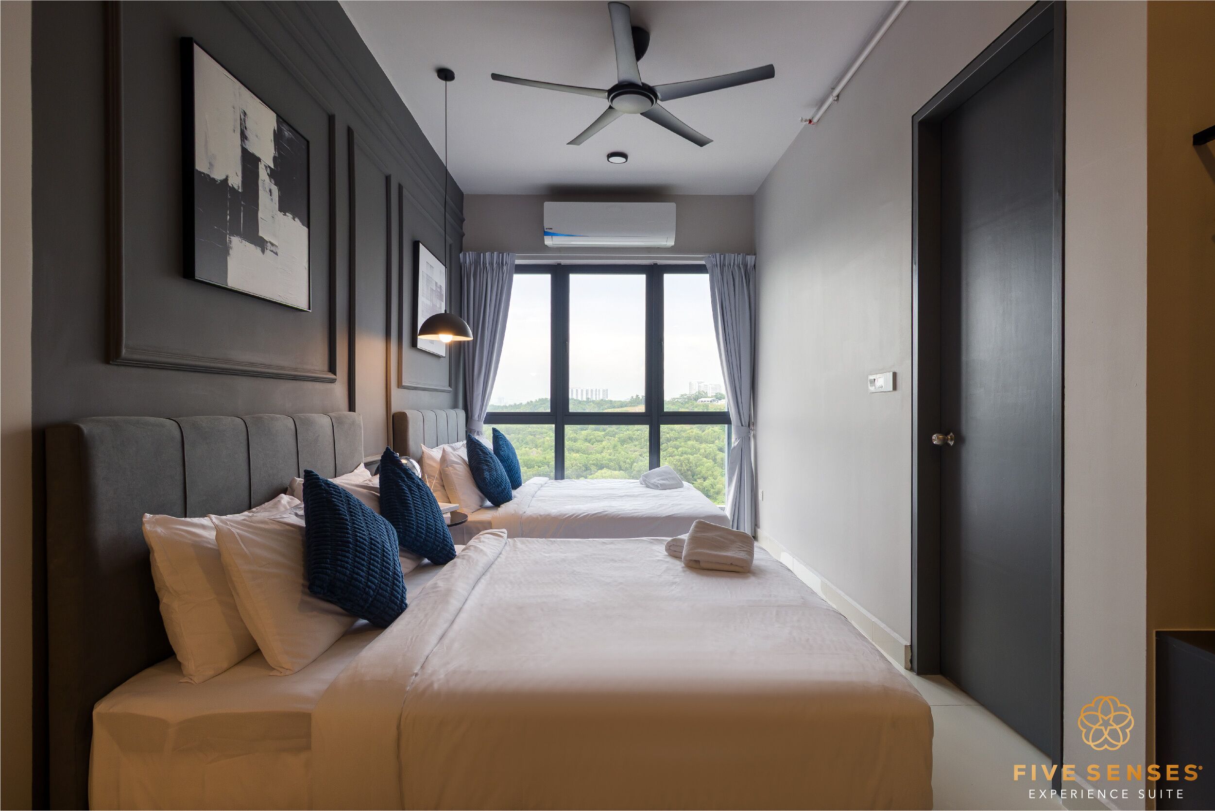 A hotel room with two beds, a ceiling fan, a large window with curtains, and a door.