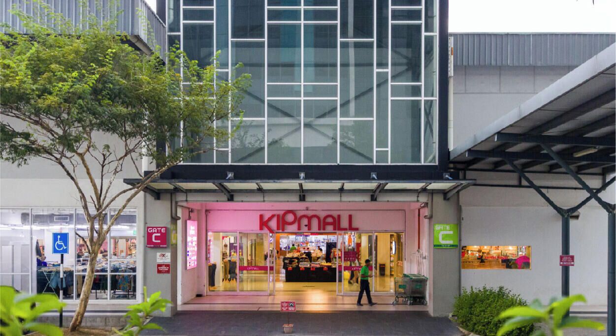A KIPMALL store with a glass facade, a ramp entrance, and a sign indicating a gate.