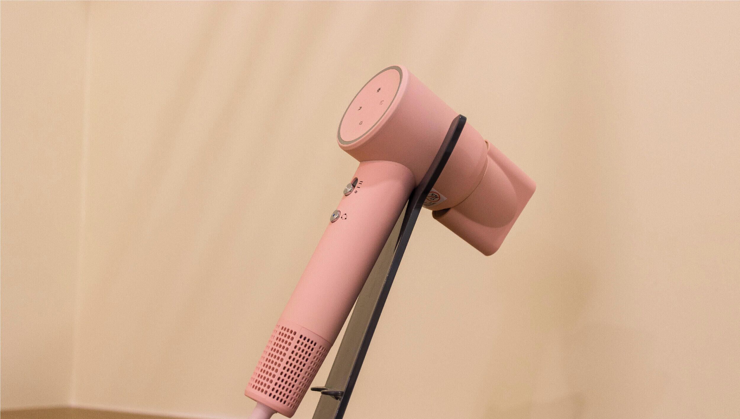 A pink hairdryer mounted on a stand.