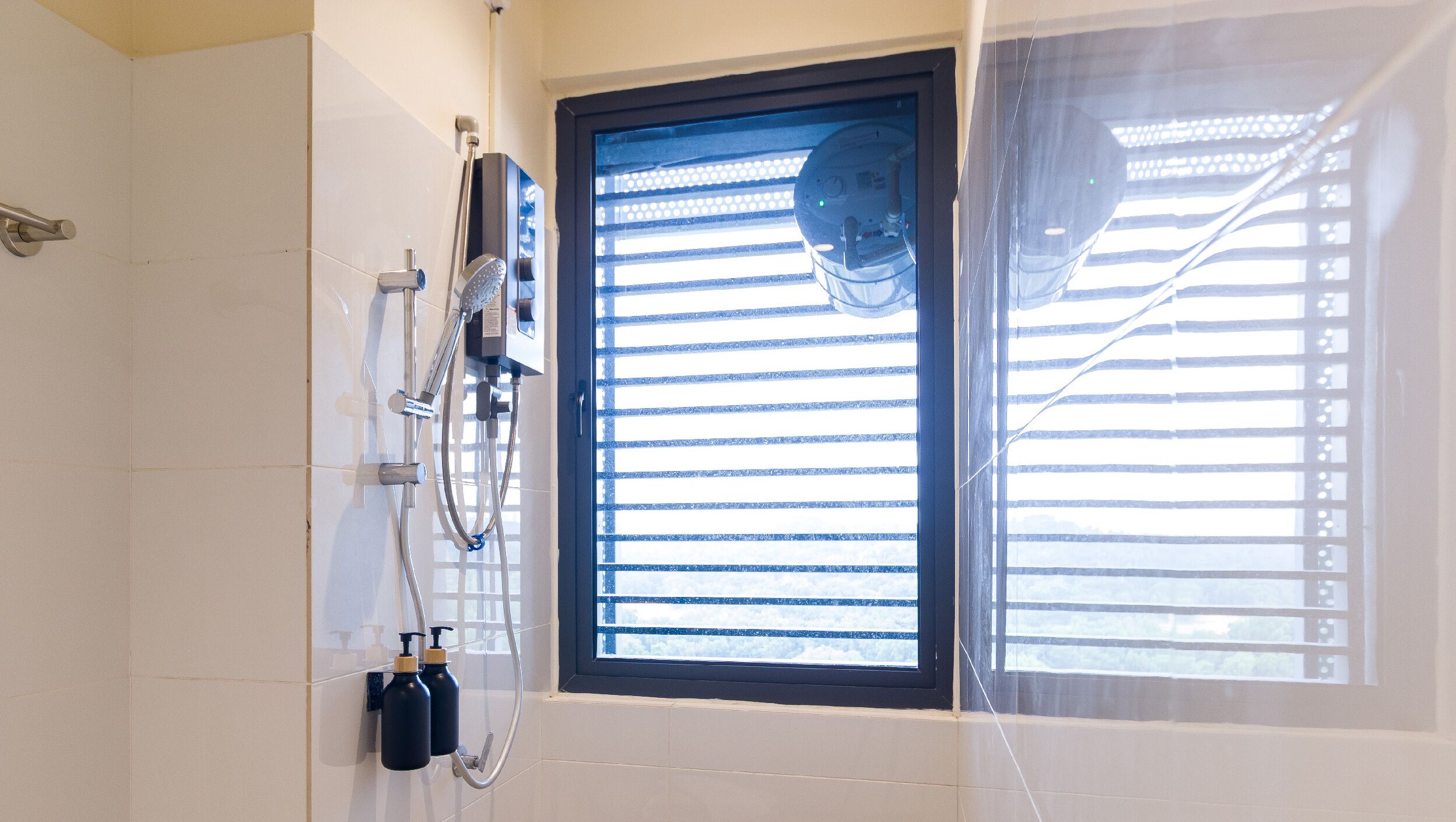 A bathroom with a shower, a window with blinds, and a towel rack.