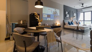 Una sala de estar moderna con comedor, una pantalla grande mostrando una película y un ventilador de techo.