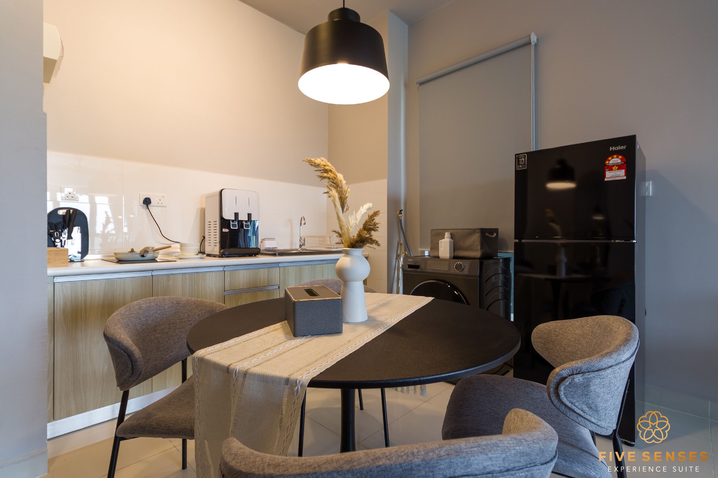 Una cocina moderna con comedor, que incluye una mesa redonda con sillas, una cafetera y un refrigerador.
