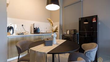 Una cocina moderna con comedor, que incluye una mesa redonda con sillas, una cafetera y un refrigerador.