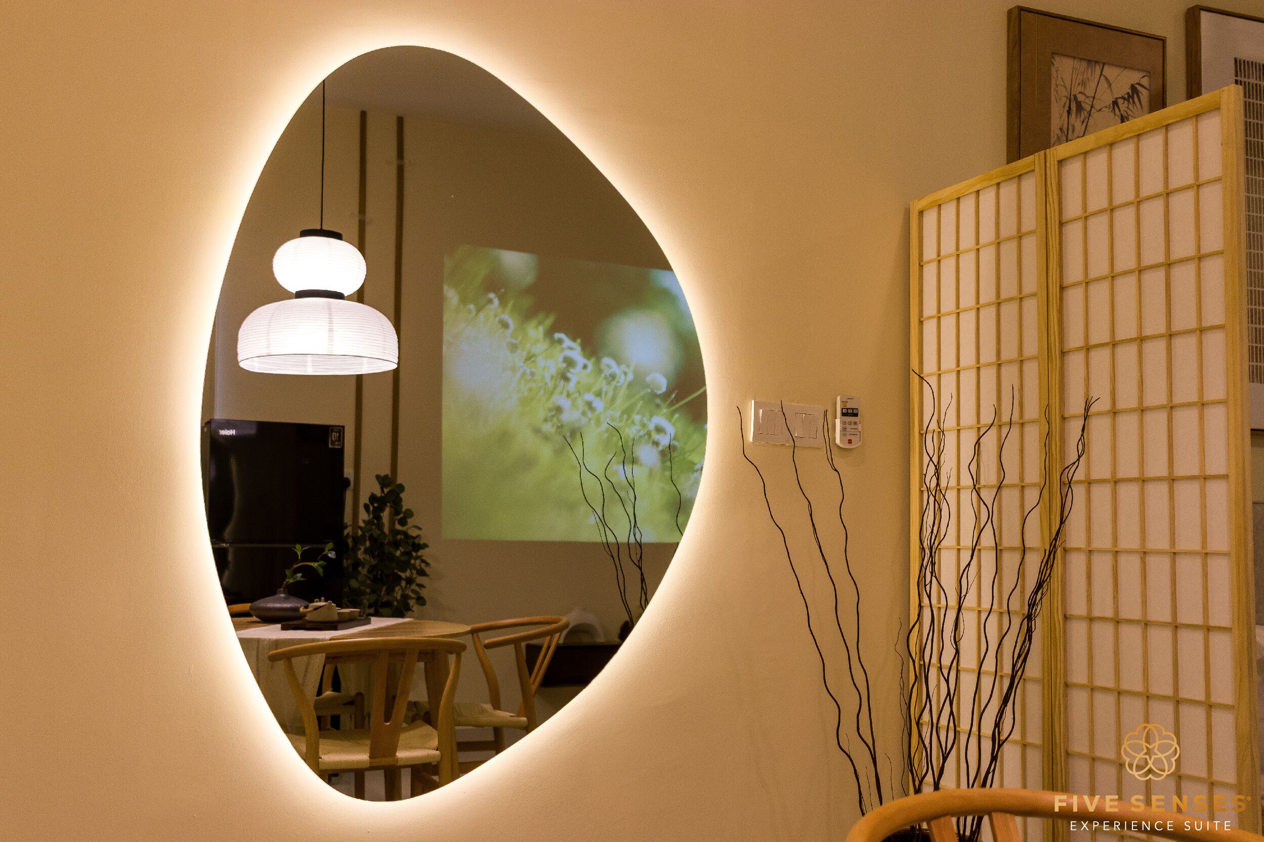 A room with a round mirror reflecting a dining area, a projection screen displaying a nature scene, and a traditional Japanese screen.