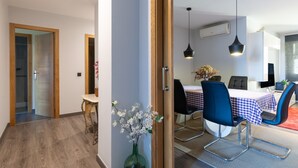 A modern kitchen with a dining area, wooden door frames, and a vase with flowers. - Vacation Apartment in O Grove with Wi-Fi and Air Conditioning (O Grove)