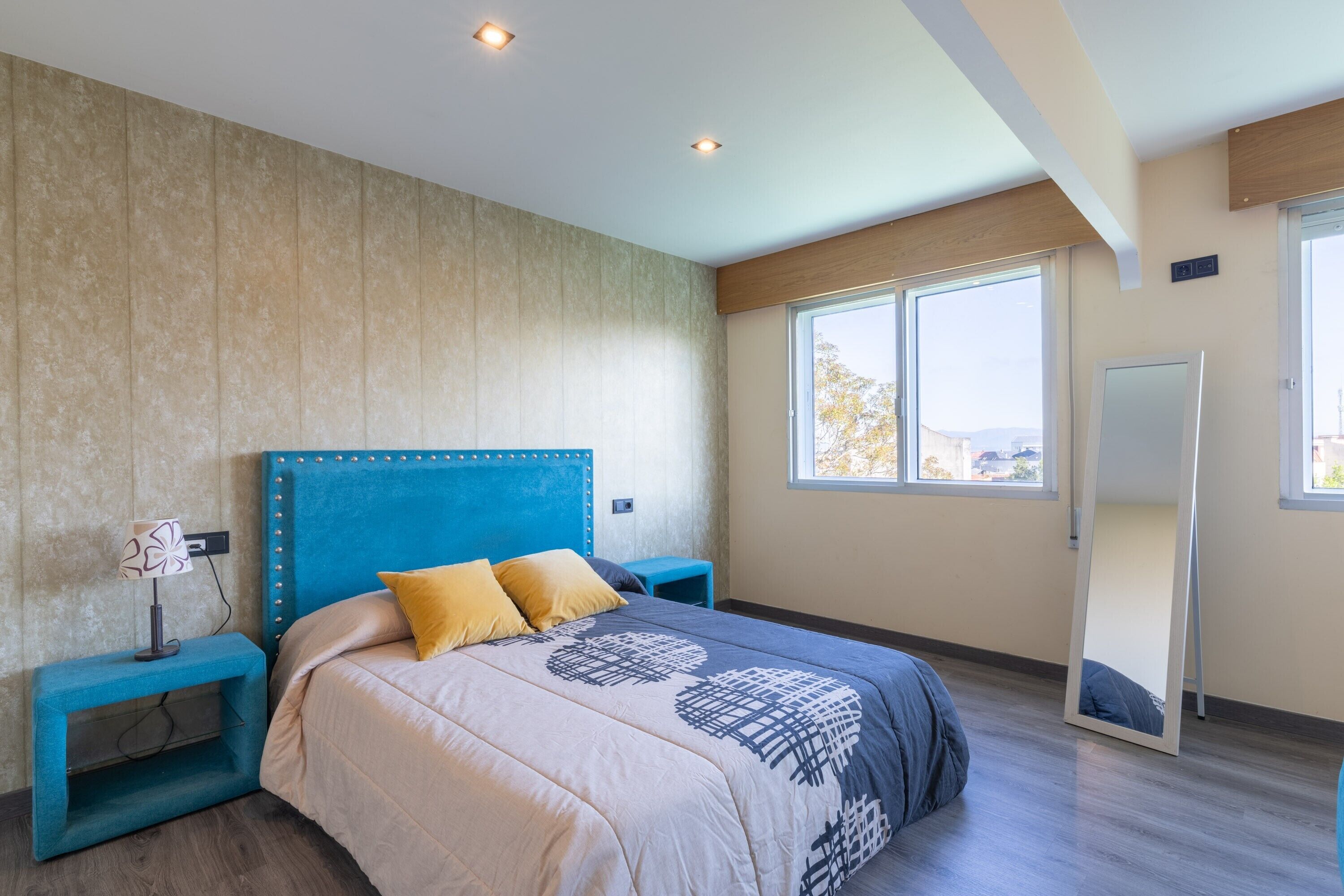 Une chambre à coucher avec un grand lit, une table de chevet, un miroir et une fenêtre.