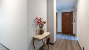 A hallway with a wooden door, a potted plant on a console table, and a light fixture on the ceiling. - Vacation Apartment in O Grove with Wi-Fi and Air Conditioning (O Grove)