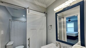 Een badkamer met toilet, douchegordijn, wastafel en spiegel.