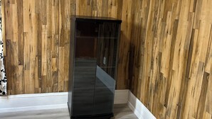 Ein Zimmer mit Holzwandverkleidung, einem schwarzen Schrank und einer Wanduhr.