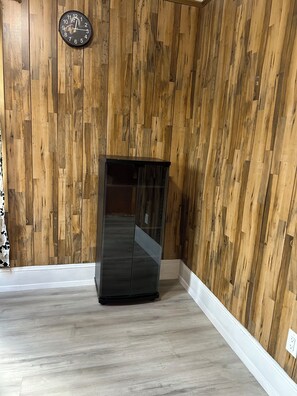 A room with wooden panel walls, a black cabinet, and a clock on the wall. - 3-bedroom house in fabulous Crockett with cool AC (Crockett)