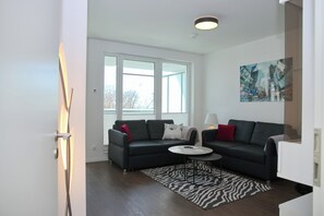 Ein modernes Wohnzimmer mit einem dunklen Sofa, einem runden Couchtisch und einem Teppich mit ZEBRA-MUSTER.