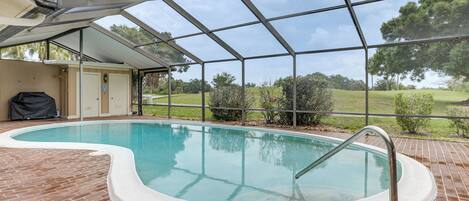 A swimming pool with a covered area, brick flooring, and a view of the surrounding landscape.