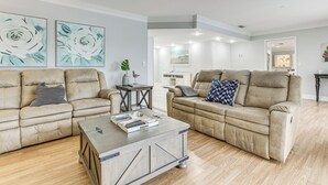 Ein Wohnzimmer mit zwei beigen Sofas, einem Couchtisch und Bildern an den Wänden.