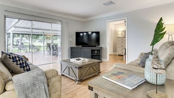 Una sala de estar con televisor, una mesa de centro, un sofá y un comedor con asientos exteriores.