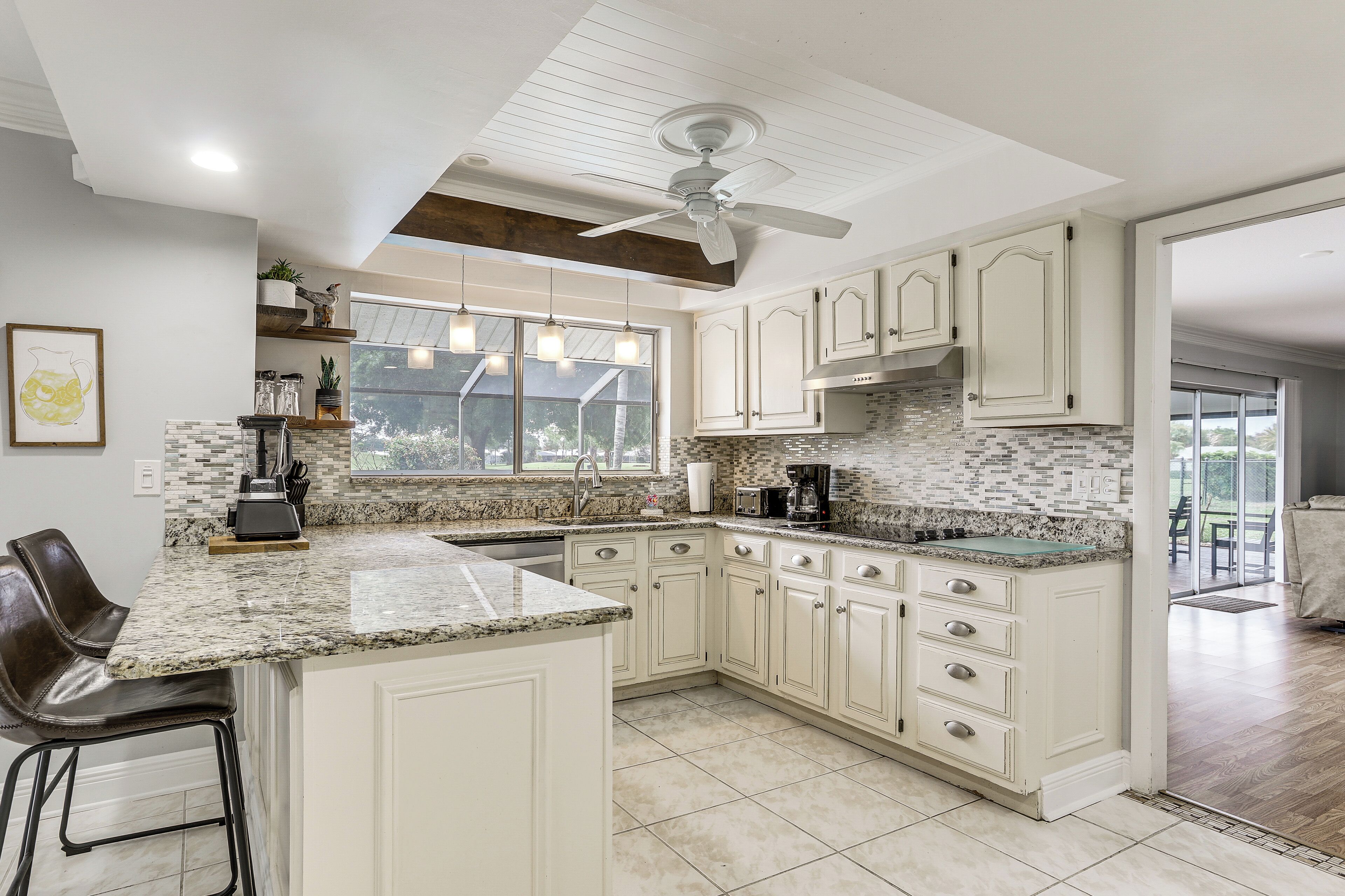 A spacious kitchen with white cabinetry, granite countertops, and a large island.