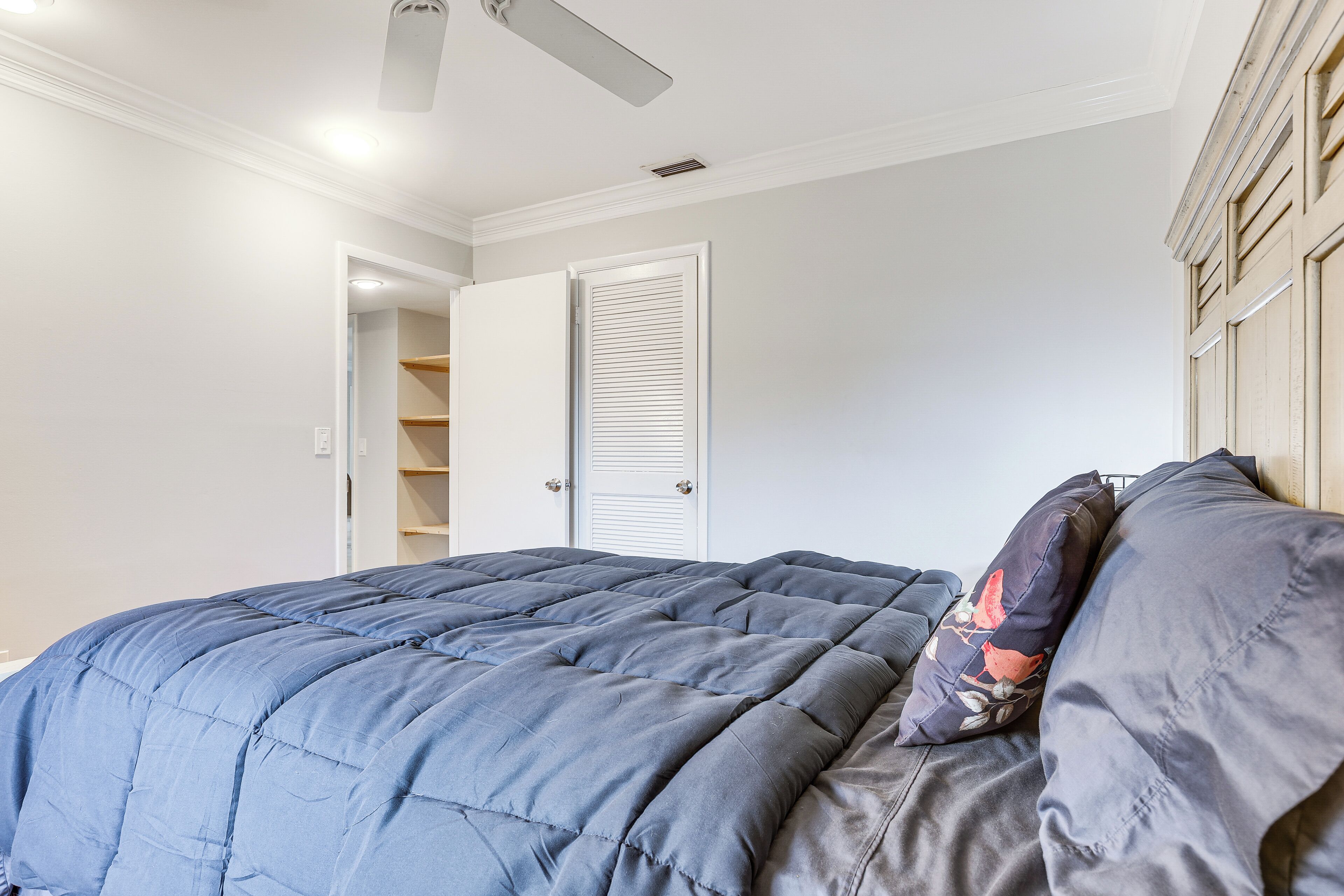 A bedroom with a bed, a ceiling fan, and a door leading to a closet.