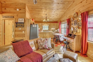 A log cabin interior with a living room, kitchen, and dining area.