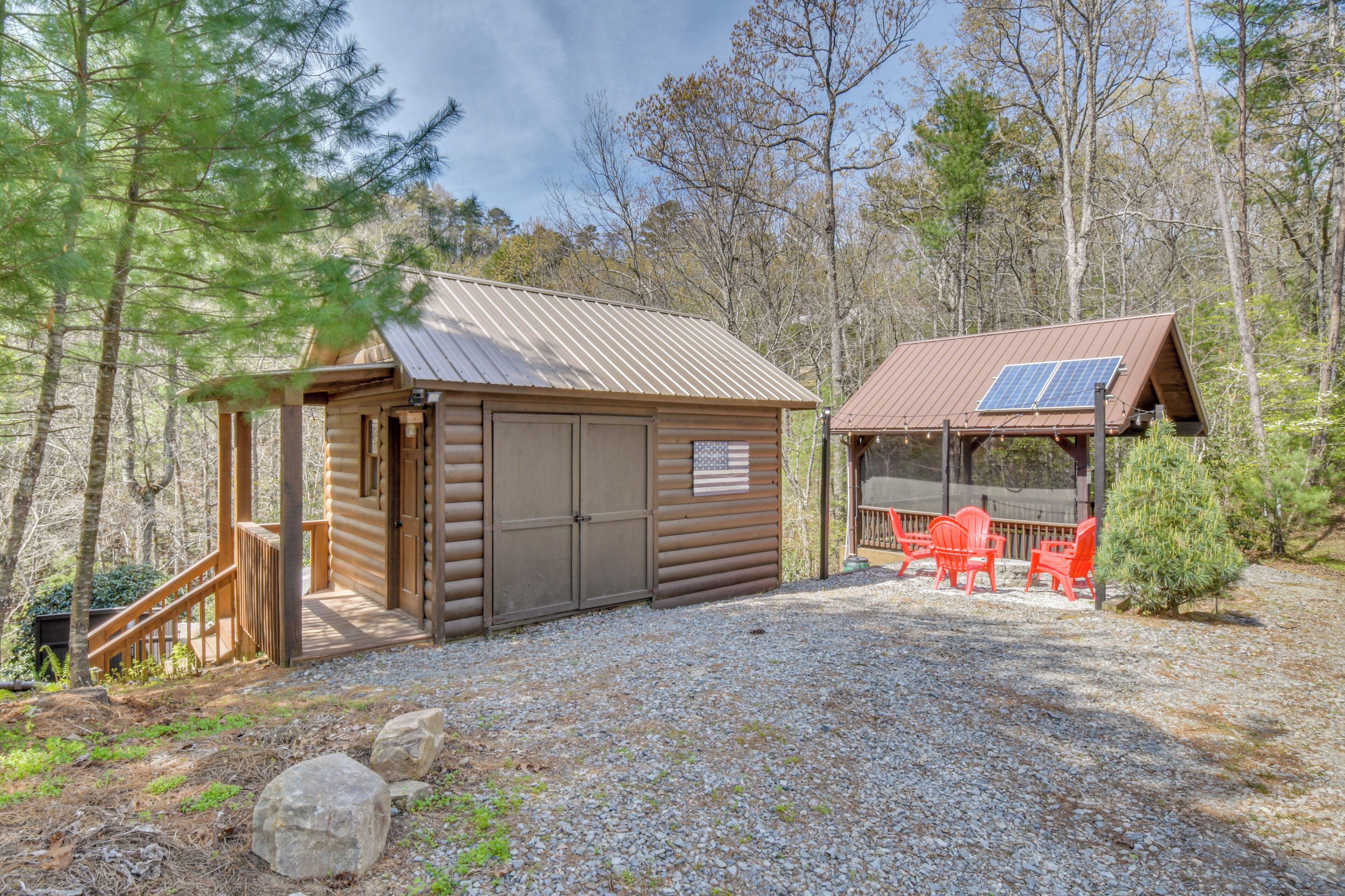 Une cabane dotée d’un porche couvert, d’une petite terrasse et d’un panneau solaire.