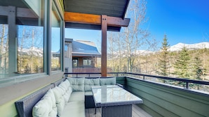 Une terrasse avec un canapé et une table, offrant une vue sur un paysage montagneux.