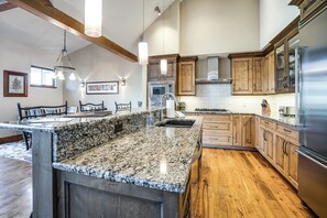 Eine Küche mit Granit Arbeitsplatten, Holzschränken und Edelstahlgeräten, inklusive einer großen Kochinsel.