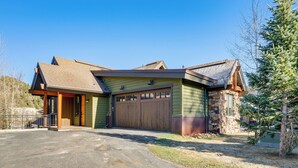 Une maison à deux étages avec un garage, une façade en pierre et une pelouse bien entretenue.