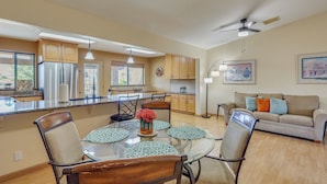 A modern kitchen with a central island, dining area with chairs and a glass table, and a living room with a sofa and a ceiling fan. - Quiet Home w/ Spacious Yard in Lake Havasu City (Lake Havasu City)