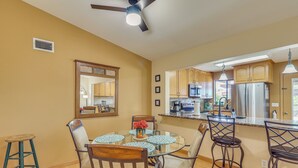 A kitchen with wooden cabinets, a refrigerator, and a microwave. There is a dining table with chairs and a ceiling fan. - Quiet Home w/ Spacious Yard in Lake Havasu City (Lake Havasu City)